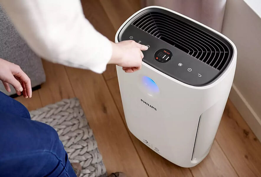 Philips laitteet sisäilman hoitoon Henkilö käyttämässä lattialle sijoitettua Philips ilmanpuhdistinta